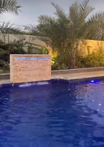 Luxury Farm Stay 50 في Badīyah: حمام سباحة به ماء أزرق وأشجار نخيل في الخلفية