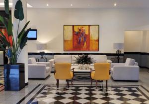a lobby with chairs and a table and a painting at Manhattan Plaza in Brasilia