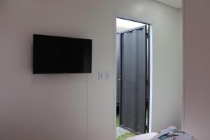 Un televisor de pantalla plana en una pared junto a una puerta. en Canela Container, en Canela 5 fotos más