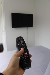 una mano sosteniendo un mando a distancia frente a un televisor en Canela Container, en Canela