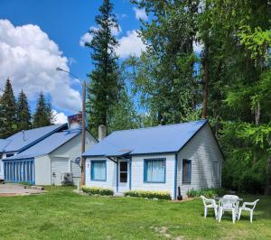 una casa con techo azul, mesa y sillas en Little River Motel Saint Regis, en Saint Regis