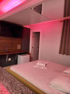 a bedroom with a white bed with pink lighting at Hotel 1001 Prime Ade Águas Claras in Águas Claras