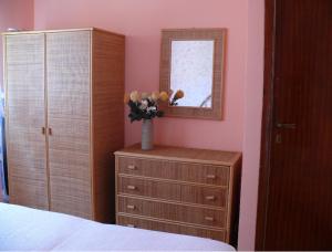 een slaapkamer met een dressoir en een spiegel en een vaas met bloemen in bij Casa Sole e Mare in Catania