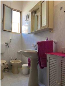 a bathroom with a sink and a toilet and purple towels at Casa Sole e Mare in Catania