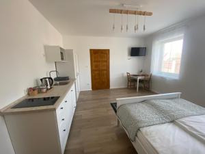 una cocina blanca con fregadero y una cama en una habitación en FarmerLand, en Abádszalók