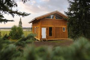 Cabaña de madera con puerta en un campo en Red Cariboo Resort, en Anahim Lake