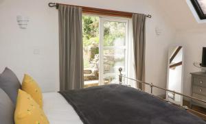 een slaapkamer met een bed en een groot raam bij Court Cottage - cosy traditional cottage near lovely beaches in Kingsbridge
