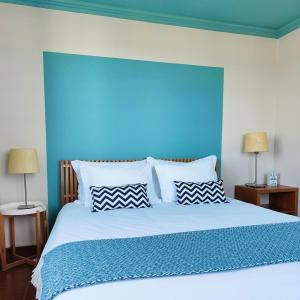 a bedroom with a large bed with a blue headboard at Flat 23 in Bombarral