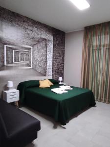 ein Schlafzimmer mit einem grünen Bett und einer Ziegelwand in der Unterkunft Vacanze Napoletane in Neapel