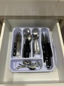 a plastic tray filled with silver utensils on a shelf at Boa Beach House in Porto Seguro