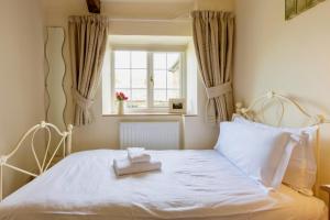 a bedroom with a white bed with a window at Character Cottage In West Burton, Wensleydale in West Burton