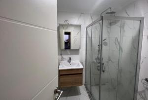 ein weißes Bad mit einer Dusche und einem Waschbecken in der Unterkunft Enoya Suites Ilıca in Cesme