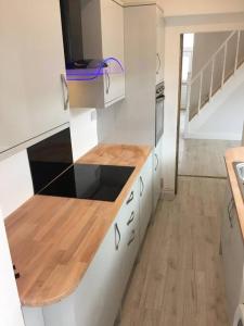 a kitchen with white cabinets and a wooden counter top at Falmouth House 3 Bedrooms 5 Beds Workstays UK in Middlesbrough