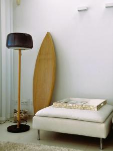 une lampe et une planche de surf contre un mur avec un banc dans l'établissement Villa Surf Vista - Praia da Areia Branca, à Lourinhã