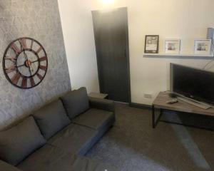 a living room with a couch and a clock on the wall at Stainsby House 4 Bedrooms Workstays UK in Stockton-on-Tees