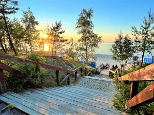 una scala in legno che conduce a una spiaggia con il tramonto di Apartament VIP Sztutolo z basenem a Sztutowo