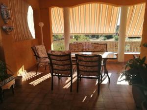 a dining room with a table and chairs and windows at chalet, villa rodeada de naturaleza con piscina cerca de la ciudad in Valencia