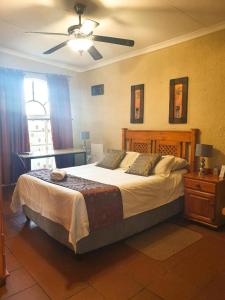 a bedroom with a large bed and a ceiling fan at Just Tiffany Guest House & Conference Facility in Potchefstroom