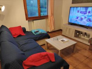 uma sala de estar com um sofá azul e uma televisão em Villetta con giardino em Camugnano
