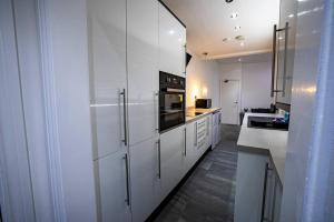 a large white kitchen with white cabinets and appliances at Roscoe House 4 Bedrooms Workstays UK in Middlesbrough