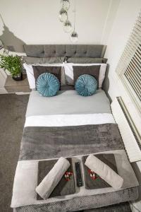 a bed with two blue pillows and two controllers at Roscoe House 4 Bedrooms Workstays UK in Middlesbrough