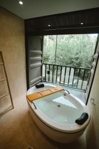 a bath tub in a room with a large window at Reserva Campos do Jordão in Campos do Jordão