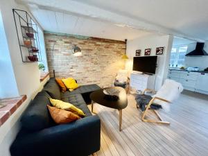 uma sala de estar com um sofá preto e uma parede de tijolos em Lækkert byhus i hjertet af Marstal em Marstal
