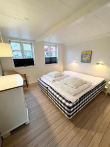um quarto com uma cama grande e 2 janelas em Lækkert byhus i hjertet af Marstal em Marstal