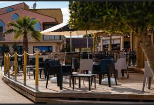 un patio con sillas, mesas y sombrillas en Dream holidays, en Valras-Plage