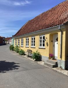 馬斯塔爾的住宿－Lækkert byhus i hjertet af Marstal，前面有长凳的黄色建筑