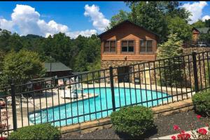a house with a swimming pool in front of a fence at Cabin With Stunning Views, Hot Tub, Game Room in Gatlinburg