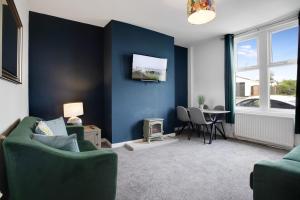 a living room with blue walls and a green couch at 2 Bed Cottage with Garden & Stunning Field Views in Durham