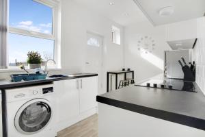a white kitchen with a washing machine and a sink at 2 Bed Cottage with Garden & Stunning Field Views in Durham