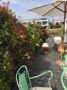 a patio with chairs and an umbrella and plants at Sunny Sea House in Rafina