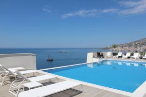 a swimming pool with chairs and a view of the ocean at The Queen's Lion Premium HOTEL in Sarandë