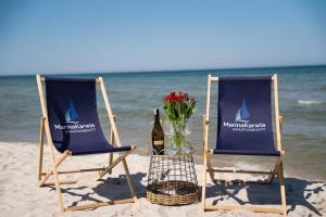 Dos sillas y una botella de vino en la playa en Karwia Marina Apartamenty, en Karwia