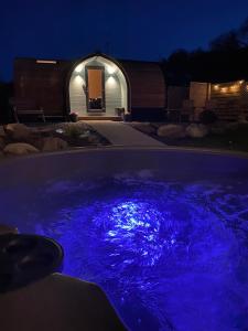 una bañera de hidromasaje con luces azules en un patio por la noche en Cwt y Gwenyn Glamping Pod en Conwy