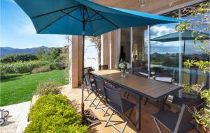 a patio with a wooden table and a blue umbrella at 5 Bedroom Gorgeous Home In Mandelieu-la-napoule in Mandelieu-La Napoule