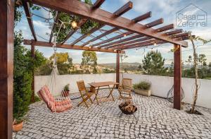 um pátio com uma pérgola de madeira, uma mesa e cadeiras em Casa Zeferina - Zeferina Family em Leiria