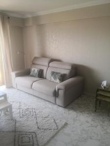 ein Wohnzimmer mit einer Couch in der Ecke in der Unterkunft Grand 2 pièces à 4mns de la plage in Cagnes-sur-Mer