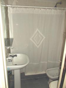 a bathroom with a sink and a toilet and a shower curtain at Hotel Barracuda in Villa Gesell