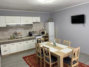 a kitchen with a table with chairs and a refrigerator at Anikó kulcsosház in Corund