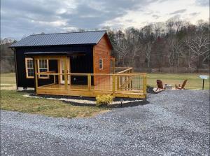 a small cabin with a porch and a fence at New Construction Pet Friendly Tiny Home W/ Hot Tub in Sevierville