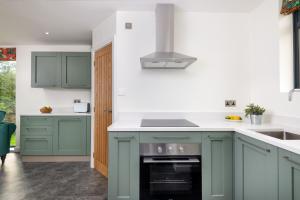 a kitchen with green cabinets and a stove top oven at Ruecroft, Penruddock in Penruddock