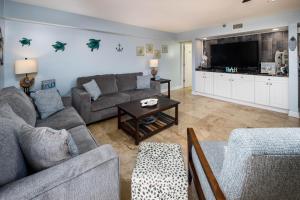 uma sala de estar com um sofá e uma televisão em Nautilus 1103 - 3 BR - Groundfloor on the beach - Free Beach Service 3/1-10/31 em Fort Walton Beach