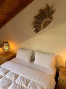 a bedroom with a bed with white sheets and a lamp at Caja De Anthea in Artemida