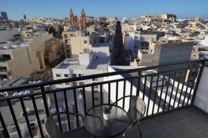 a balcony with chairs and a view of a city at The Londoner Hotel Sliema in Sliema
