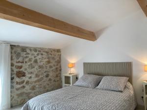 a bedroom with a bed and a stone wall at Gîte de 12 personnes au cœur d'un domaine viticole in Gruissan