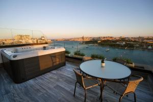 a hot tub on a roof with a table and chairs at The Londoner Hotel Sliema in Sliema