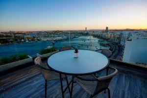 a table and chairs on a balcony with a view of a city at The Londoner Hotel Sliema in Sliema